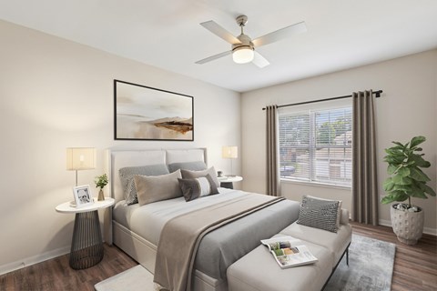 A bedroom with a large bed, a ceiling fan, and a potted plant.