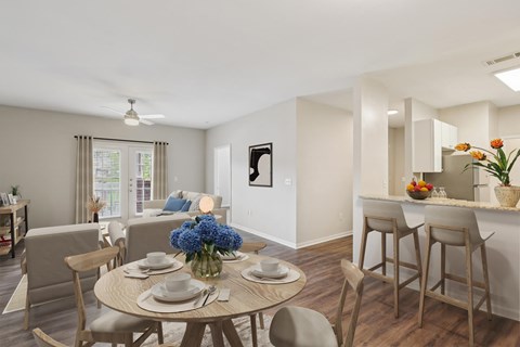 A dining room with a table set for two and a vase of flowers.