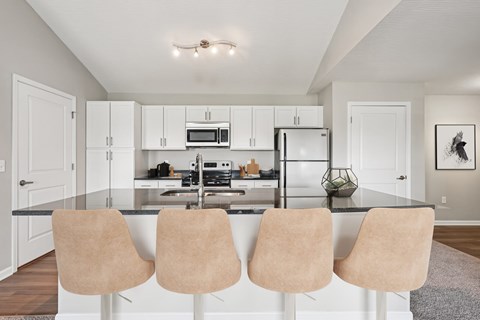 A kitchen with white cabinets and a black countertop.
