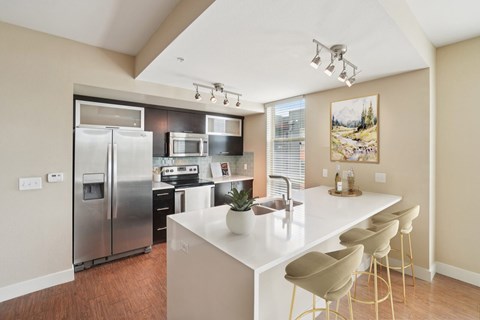 A kitchen with a white counter top and stainless steel appliances.