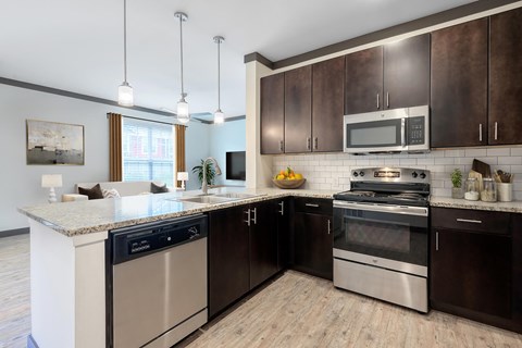 A modern kitchen with dark brown cabinets and stainless steel appliances.