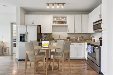 A modern kitchen with a table and chairs in the middle.