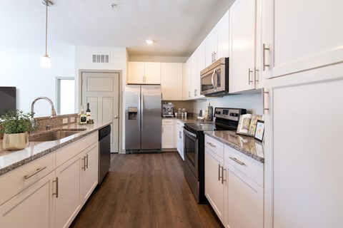 A modern kitchen with white cabinets and stainless steel appliances.