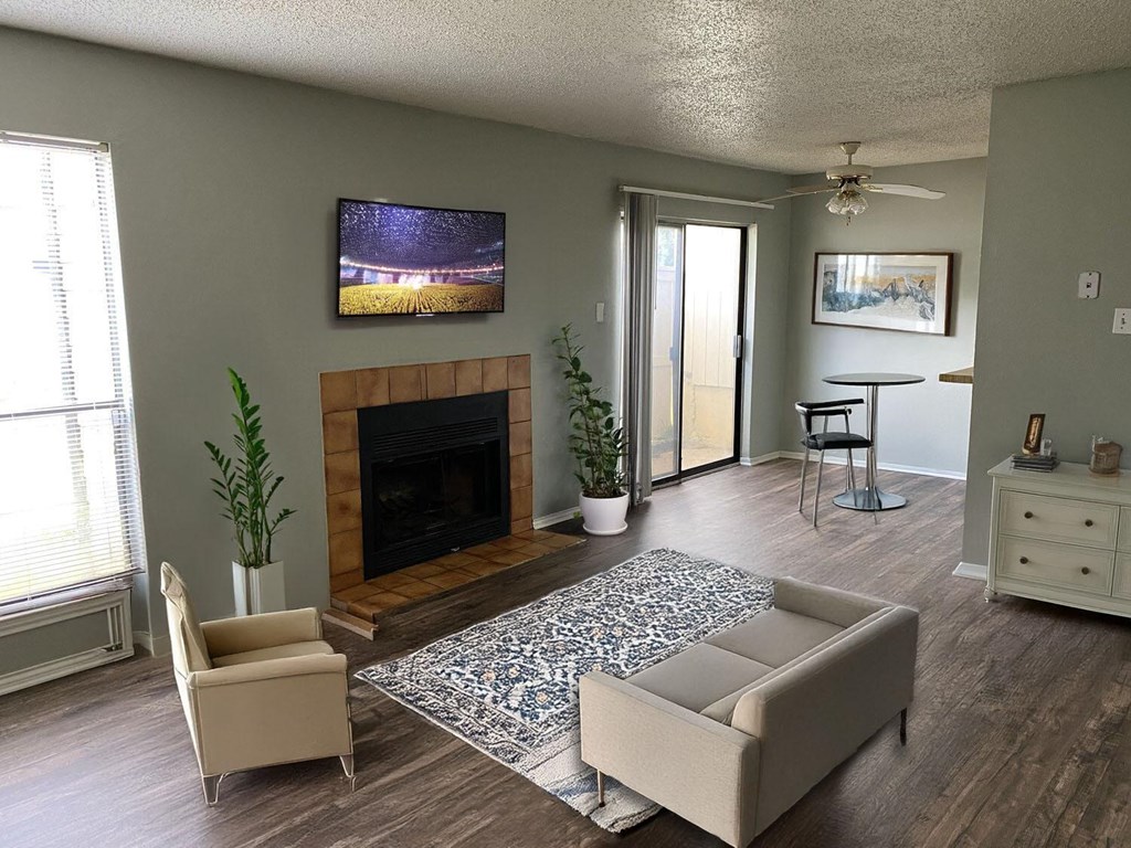 A living room with a fireplace and a television mounted above it.