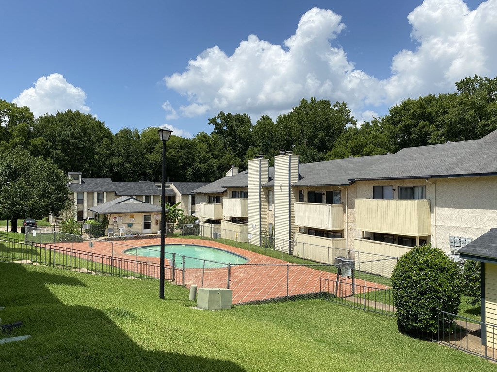 A pool surrounded by a fence in a grassy area.