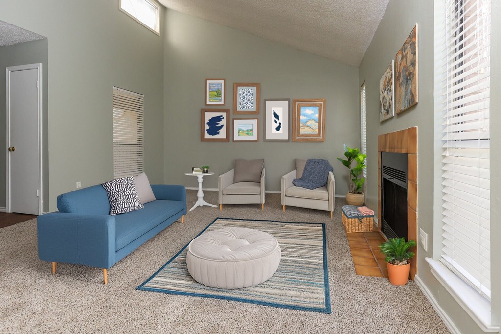 A living room with a blue couch, a white ottoman, and a fireplace.