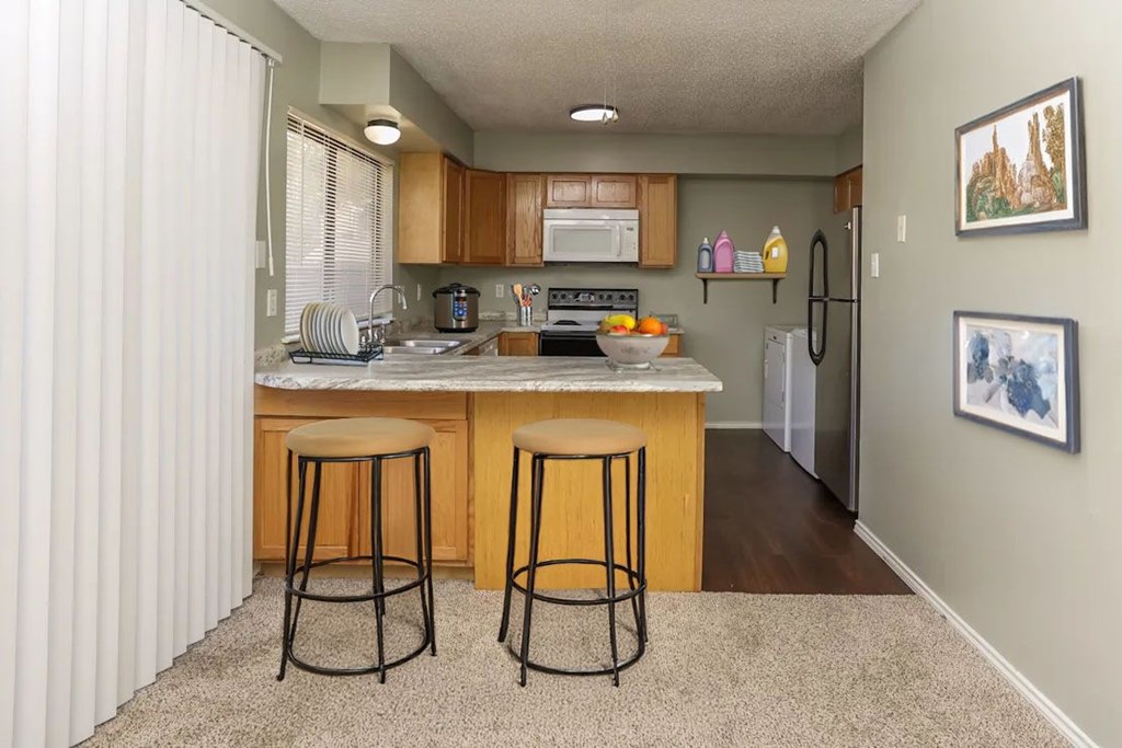 A kitchen with a bar stool in front of it.