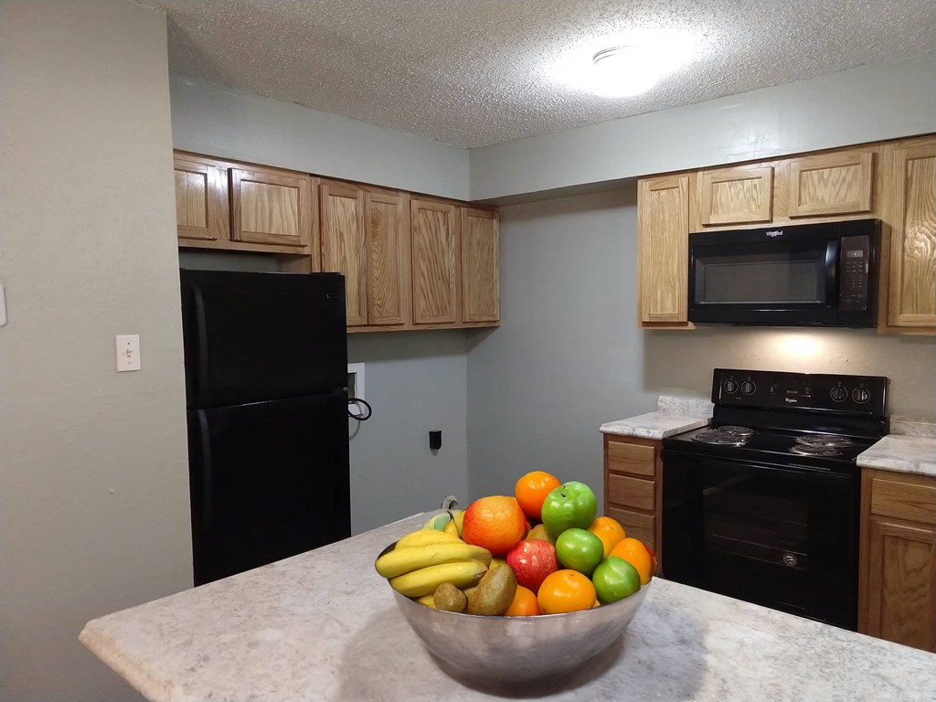 A bowl of fruit sits on a counter in a kitchen.