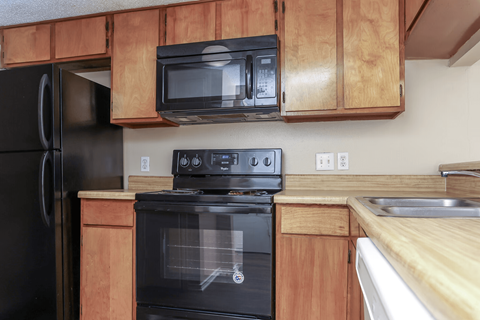 A black oven is in a kitchen with wooden cabinets.