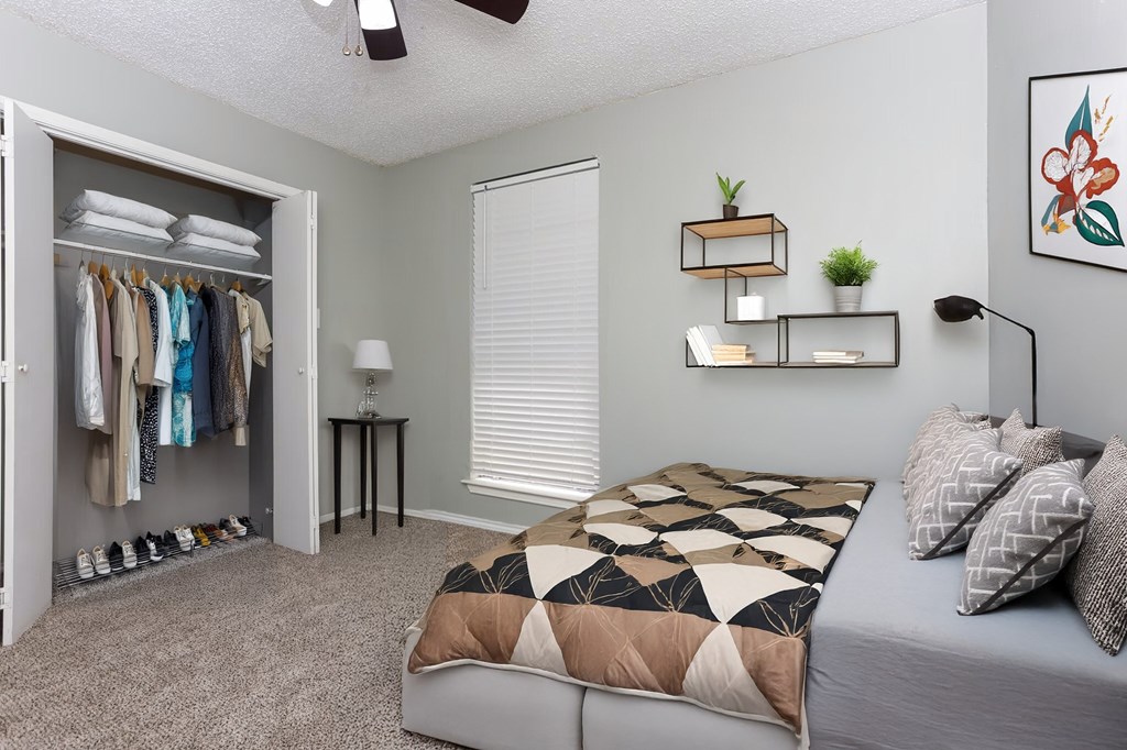 A bedroom with a bed, a clothing rack, and a ceiling fan.