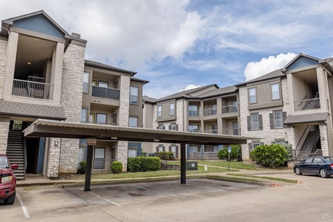 Apartment complex with a parking lot in front.