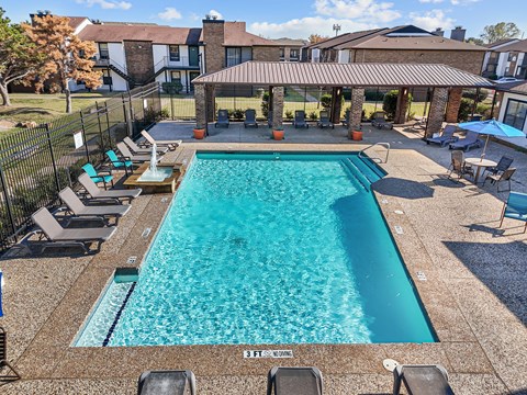 A large outdoor swimming pool surrounded by lounge chairs and umbrellas.