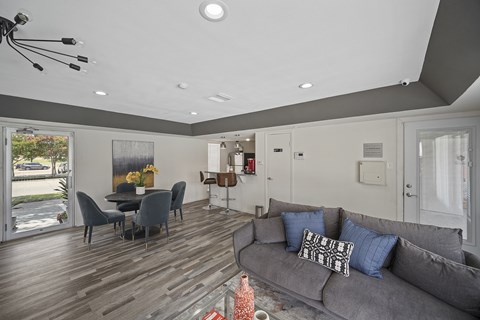 A modern living room with a grey couch and a dining table.