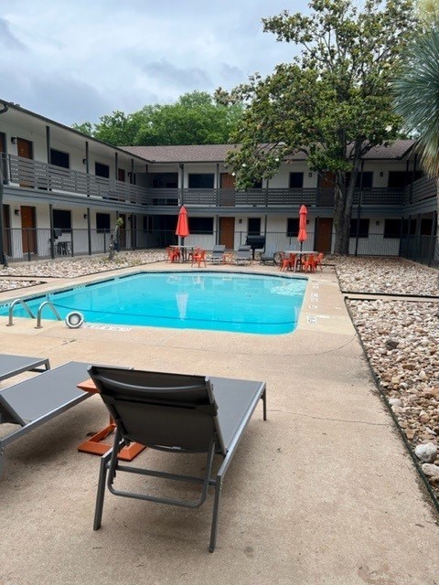 A pool area with chairs and a table.