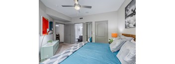A bedroom with a blue bedspread and a ceiling fan.