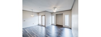 A spacious room with a ceiling fan and hardwood flooring.