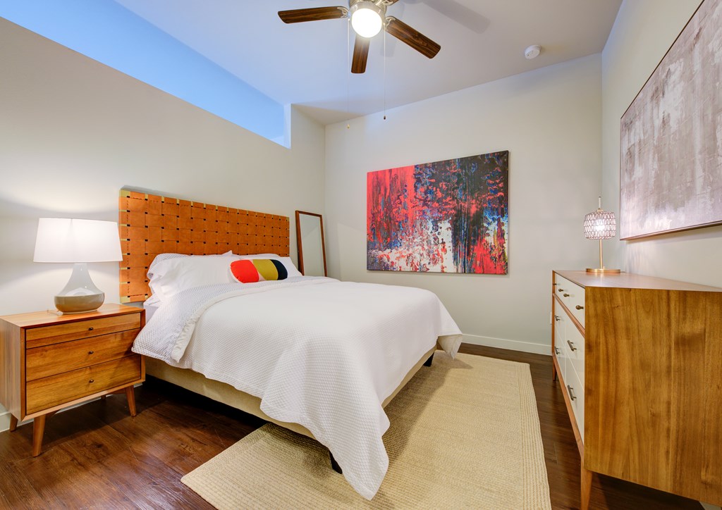 A bedroom with a bed, dresser, and painting.