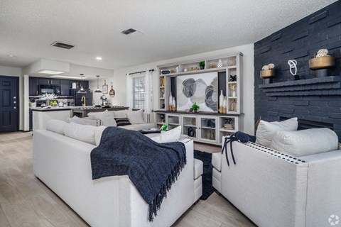A modern living room with a white couch and a kitchen area in the background.
