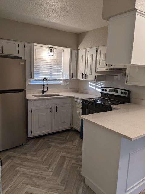A kitchen with a refrigerator, stove, and cabinets.