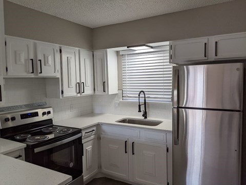 A kitchen with white cabinets and a stainless steel refrigerator.
