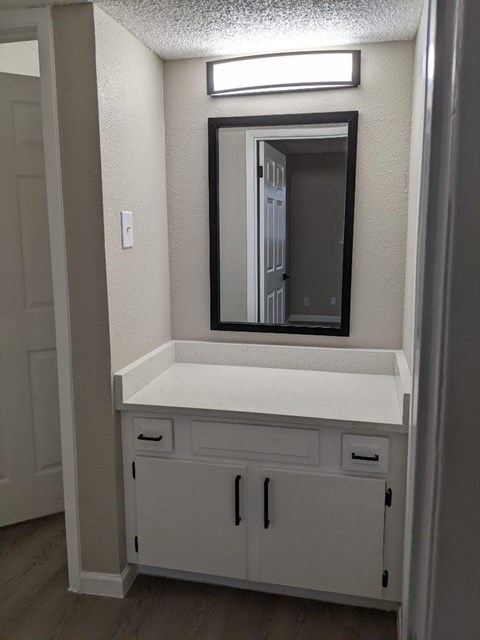 A white vanity with a mirror and a light above it.