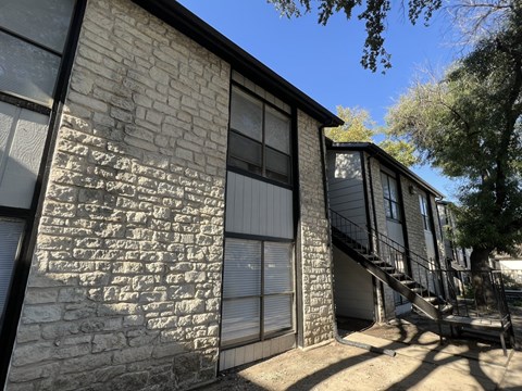 A building with a stone wall and a metal staircase.