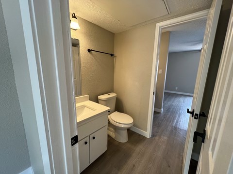 A bathroom with a toilet, sink, and mirror.