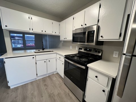 A kitchen with white cabinets and appliances.