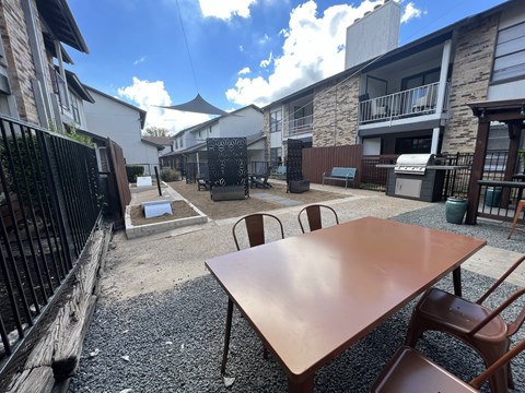 A patio with a table and chairs is surrounded by buildings.