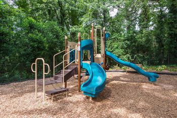 A playground with a blue slide and a brown wooden platform.
