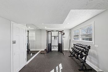 A home gym with a variety of equipment including a treadmill, weights, and a bench press.