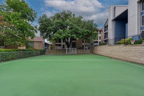 A tennis court surrounded by trees and buildings.
