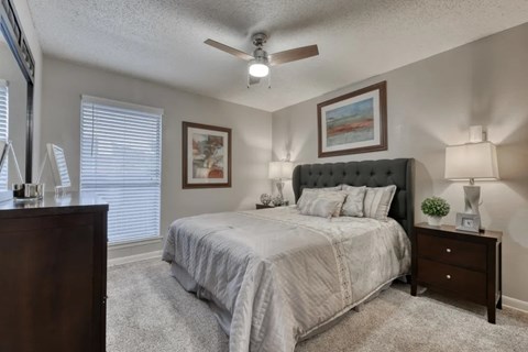 A bedroom with a bed, nightstand, and a painting on the wall.