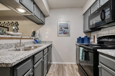 A kitchen with granite countertops and a black stove top oven.