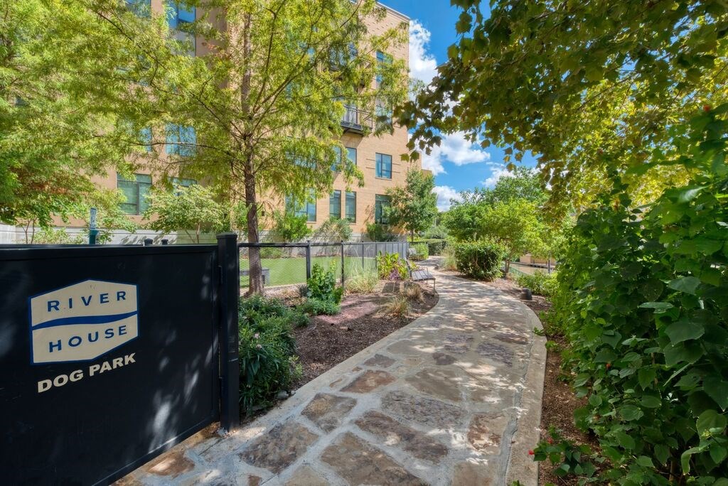 A sign that says River House Dog Park is in front of a building.