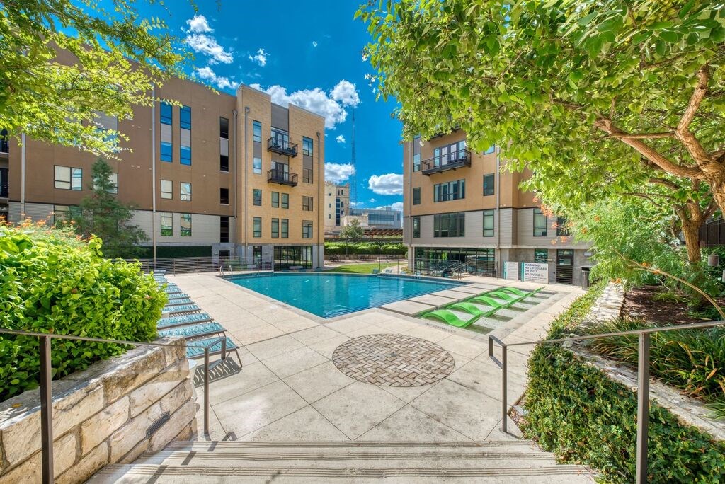 A swimming pool surrounded by a concrete fence and a building in the background.