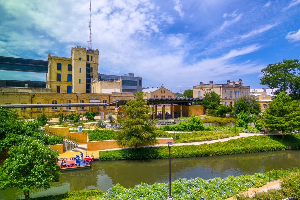 A river runs through a city park with a boat on the water.