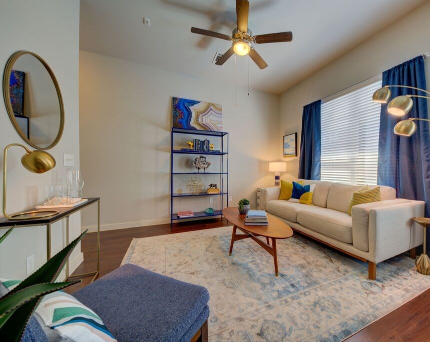 A living room with a white couch, a coffee table, and a ceiling fan.