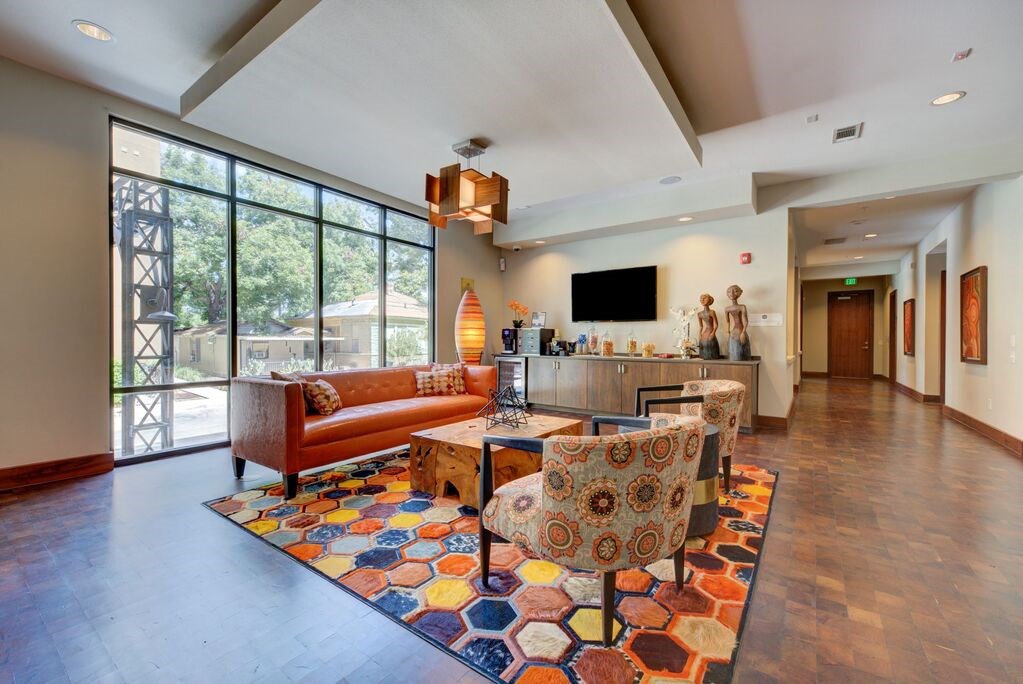 A living room with a brown couch and a colorful rug.