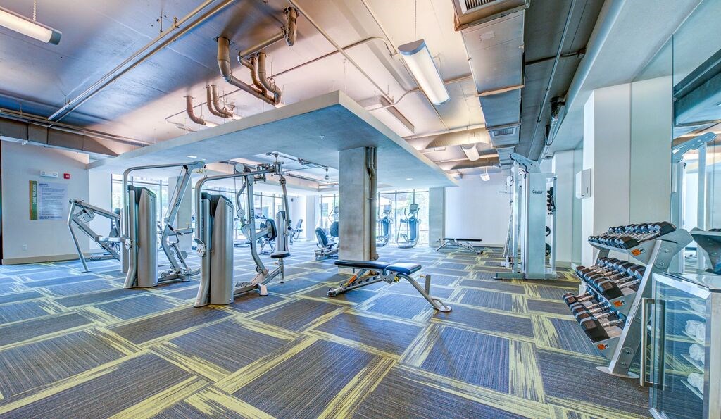 A gym with a variety of equipment including treadmills, weights, and exercise machines.