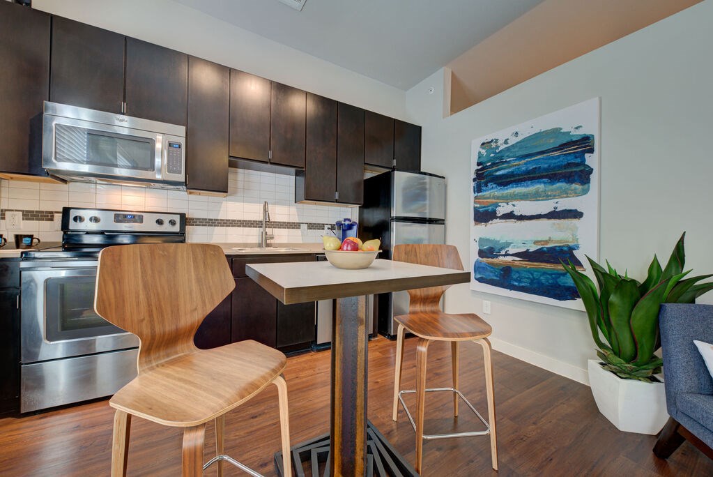 A modern kitchen with a wooden chair and a painting on the wall.