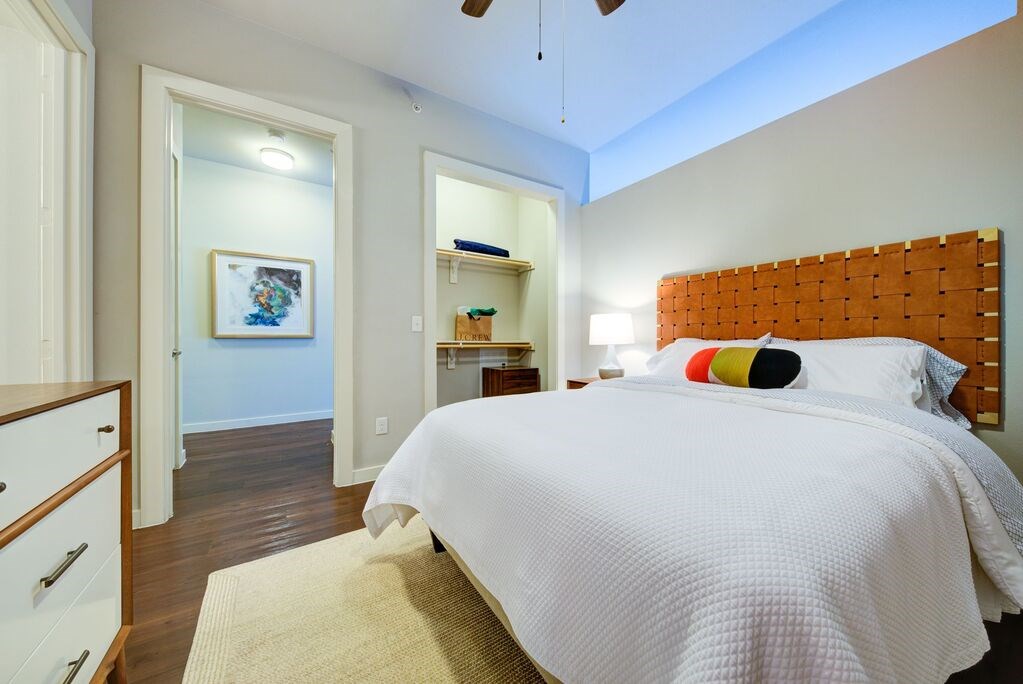 A bedroom with a bed, a dresser, and a painting on the wall.