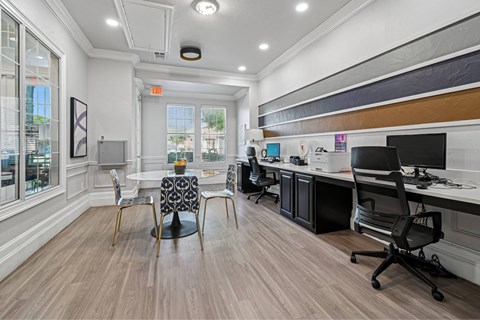 A modern office space with wood flooring and a variety of chairs and desks.