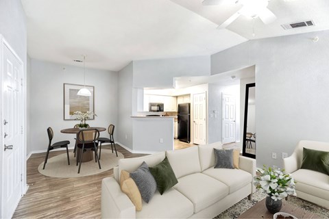 A living room with a white couch and a dining table with chairs.