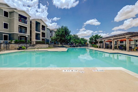 A swimming pool in front of a building with a clear blue sky above.