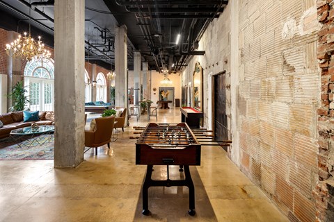 A room with a shiny wooden table and a brick wall.