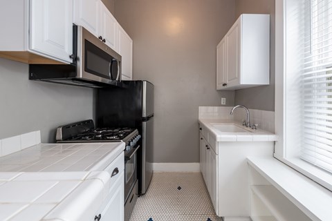 A kitchen with white cabinets and black appliances.