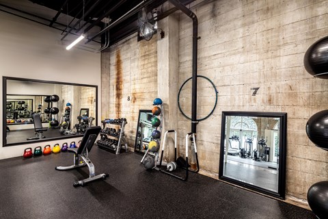 A gym with a variety of equipment including a weight bench, a mirror, and a punching bag.