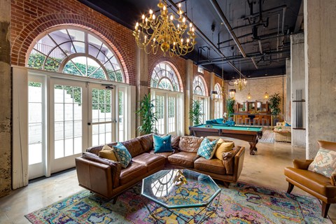 A living room with a brown leather couch and a chandelier.