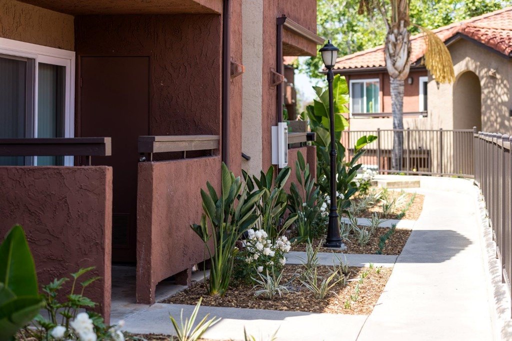 A brown house with a white door and a small garden in front.